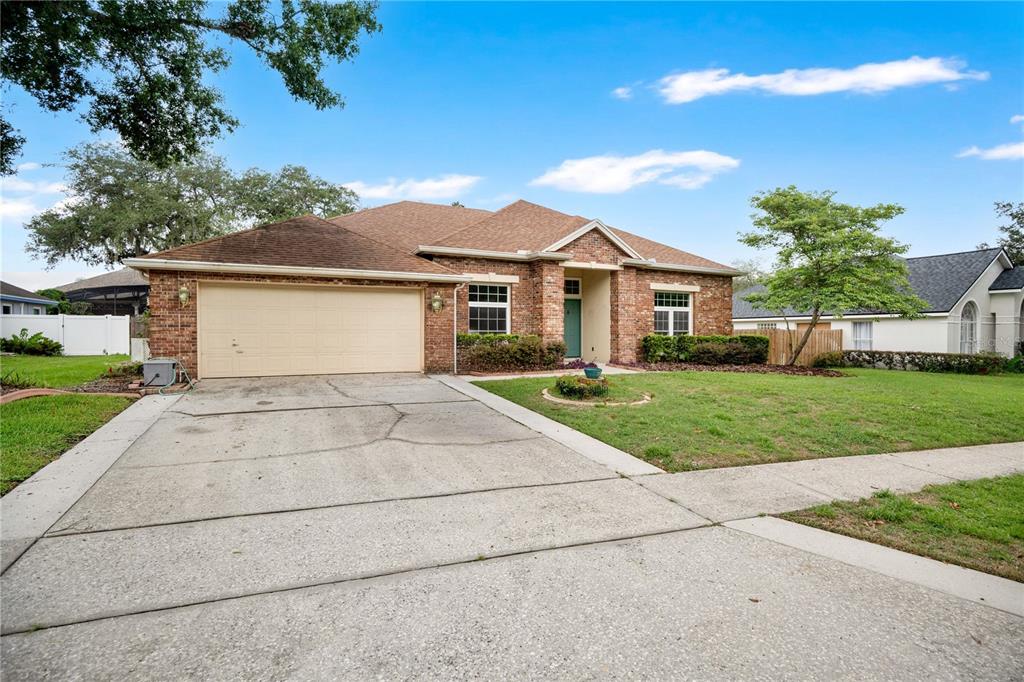 A single-story brick house with a two-car garage and a concrete driveway — 3886 KINGSTON OAKS COVE, OVIEDO, FL