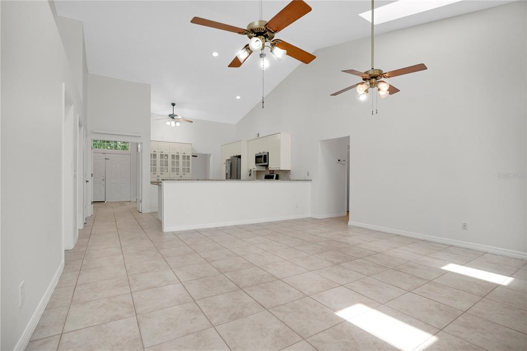 A spacious, open-concept living area features vaulted ceilings, tile flooring, and a kitchen island — 3886 KINGSTON OAKS COVE, OVIEDO, FL