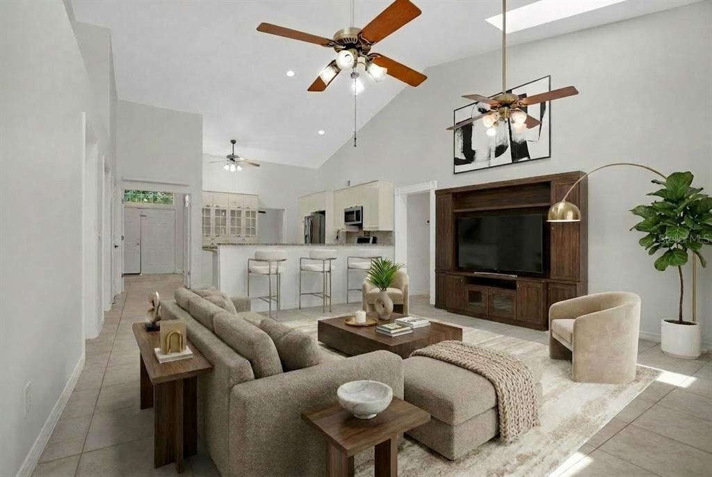 An open-concept living room and kitchen featuring vaulted ceilings, tile floors, and wood cabinetry — 3886 KINGSTON OAKS COVE, OVIEDO, FL
