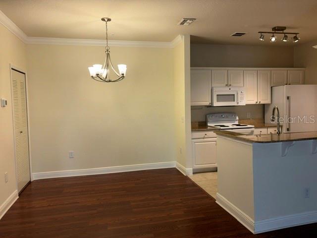 A dining area with a chandelier sits adjacent to a kitchen featuring white cabinets — 143 SOUTHERN PECAN CIRCLE UNIT 206, WINTER GARDEN, FL