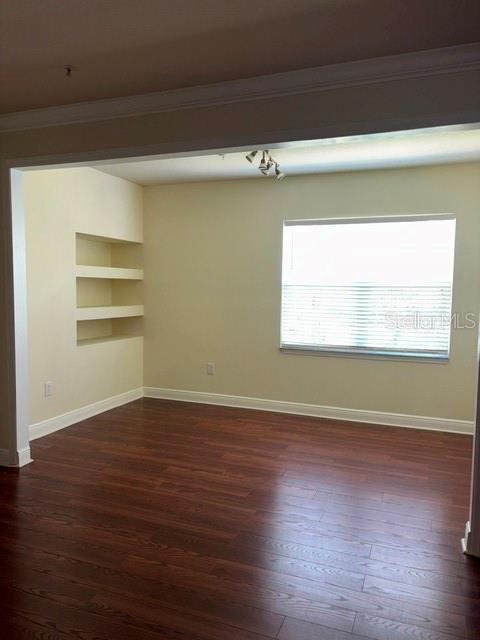 An empty room features dark wood flooring, light-colored walls, a window, and built-in wall shelves — 143 SOUTHERN PECAN CIRCLE UNIT 206, WINTER GARDEN, FL