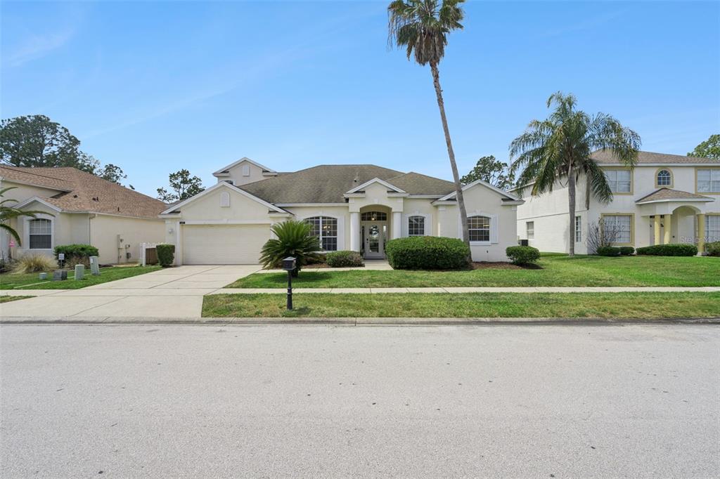 A single-story suburban house with a two-car garage, palm trees, and a manicured lawn — 117 N HAMPTON DRIVE, DAVENPORT, FL