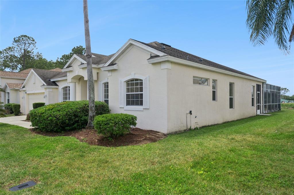 A side view of a light-colored stucco house with a screened-in patio and lawn — 117 N HAMPTON DRIVE, DAVENPORT, FL
