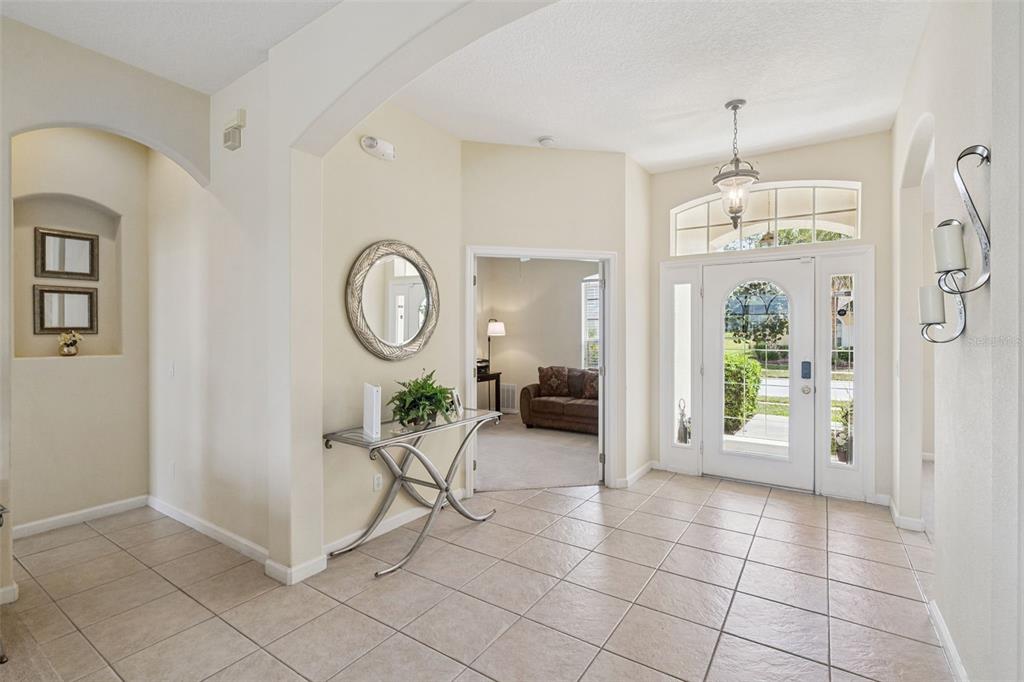 A tiled foyer features a glass-topped console table, a round mirror, and a front door — 117 N HAMPTON DRIVE, DAVENPORT, FL