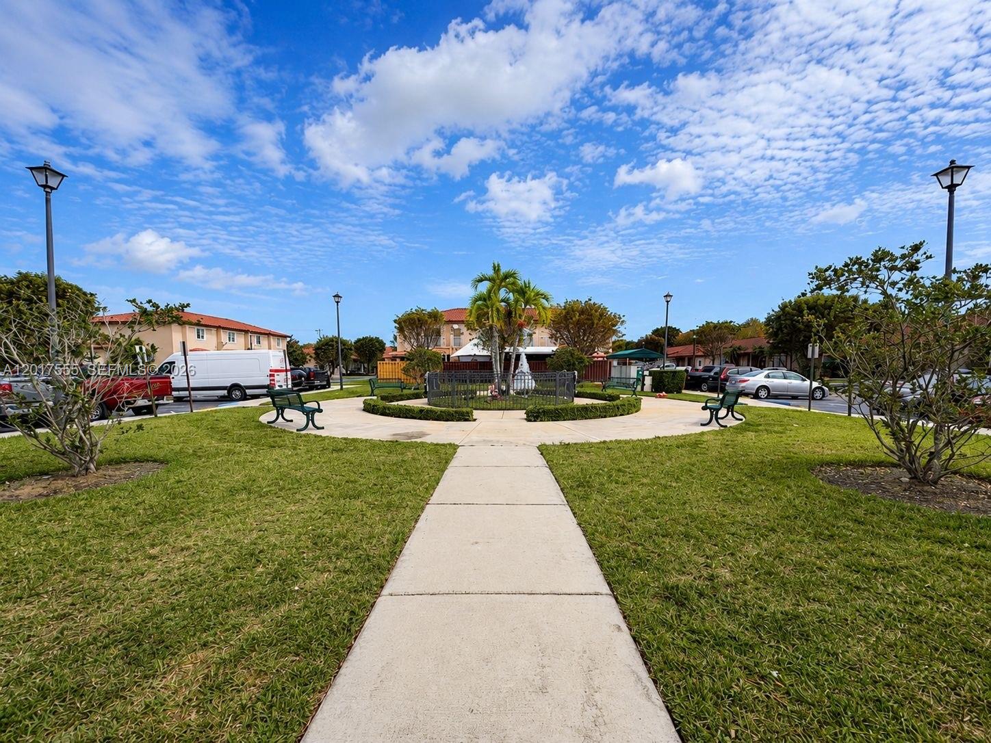 A paved walkway leads through a grassy courtyard with benches and a central palm tree — 17184 SW 138th Ct, Miami FL 33177, MIAMI, FL