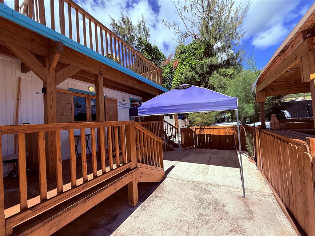 A wooden deck with stairs leads to a building entrance under a blue canopy tent — CARR. #3 BEACH FRONT VILLA, PATILLAS, PR