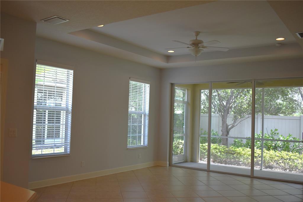 A bright living room features tile floors, a tray ceiling with a fan, and sliding doors — 2585 CORTENOVA COURT, VENICE, FL