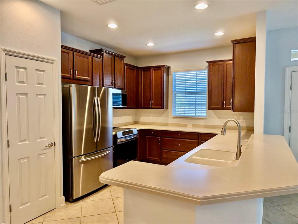 A kitchen features dark wood cabinets, stainless steel appliances, and a light-colored countertop — 2585 CORTENOVA COURT, VENICE, FL