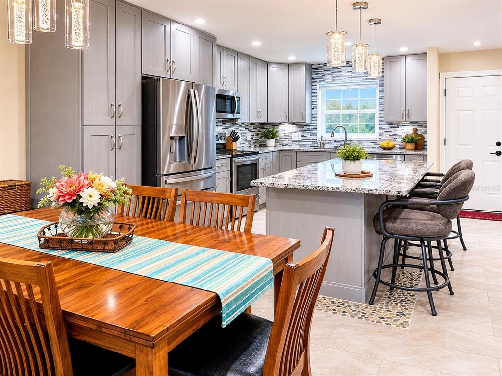 A kitchen with gray cabinets, granite countertops, a center island, and an adjacent dining area — 1640 JUNO TRAIL UNIT 102D, ASTOR, FL