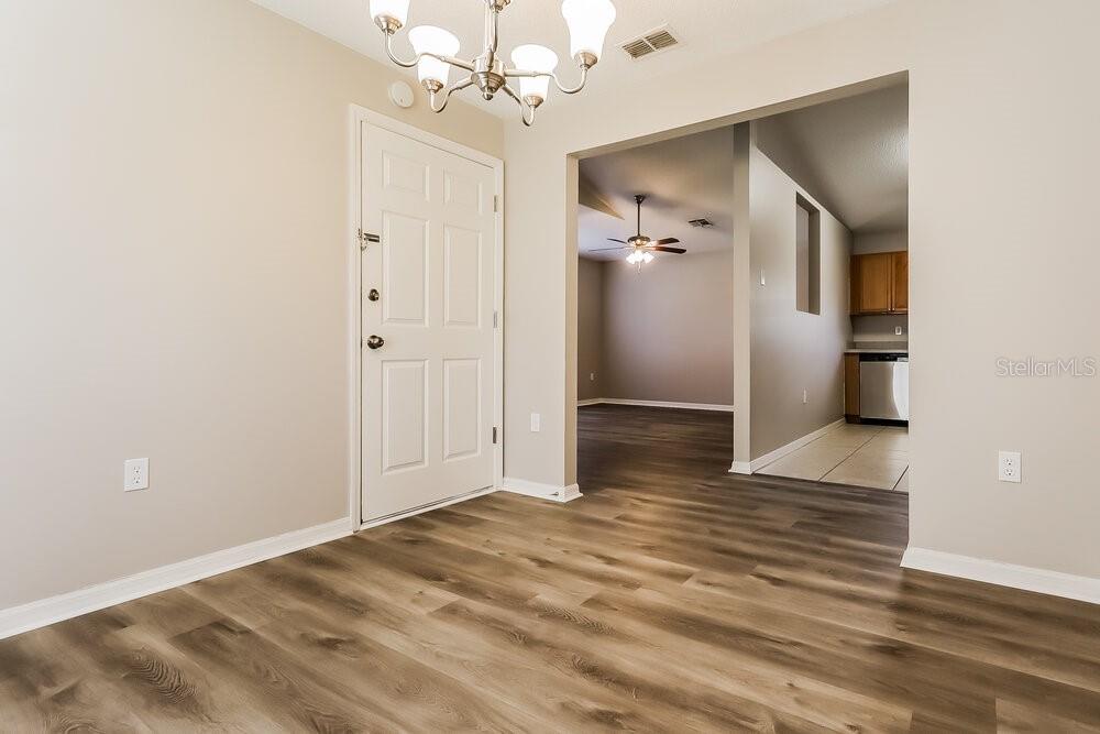 An entryway with wood-look flooring leads to a living area and a kitchen — 11730 LYNN BROOK CIRCLE, SEFFNER, FL