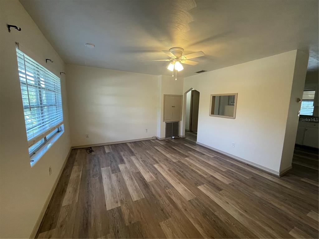 An empty room features wood-look vinyl flooring, a ceiling fan, and a window with blinds — 143 E SOUTH STREET, DELAND, FL