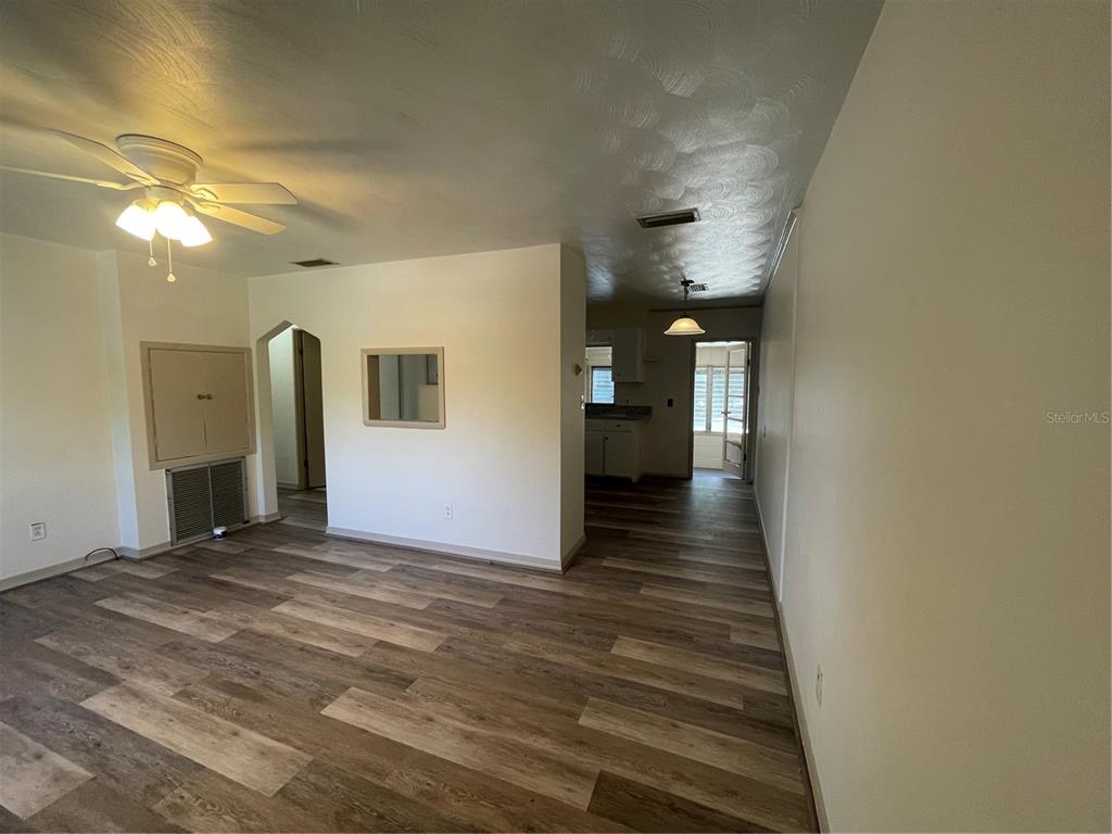 An interior view shows a living area with wood-look flooring and a ceiling fan — 143 E SOUTH STREET, DELAND, FL