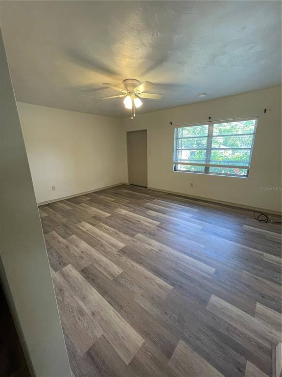 An empty room features light-colored wood-look flooring, a ceiling fan, and a single window — 143 E SOUTH STREET, DELAND, FL