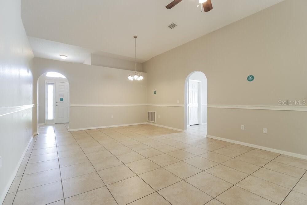 An empty room with beige tile flooring, a dining area, and arched doorways — 2959 ELBIB DRIVE, ST CLOUD, FL