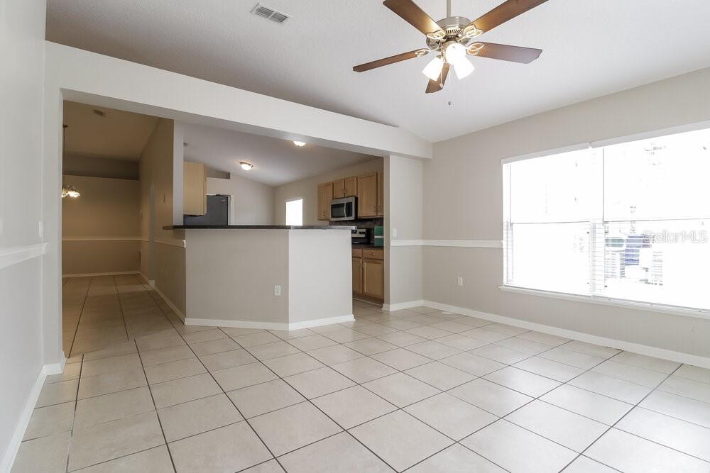 An open-concept living area features light tile flooring, a ceiling fan, and a kitchen pass-through — 2959 ELBIB DRIVE, ST CLOUD, FL