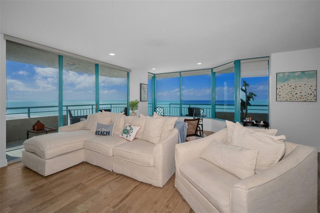 A living room with light-colored furniture and large windows overlooking the ocean — 1520 GULF BOULEVARD UNIT 1201, CLEARWATER BEACH, FL