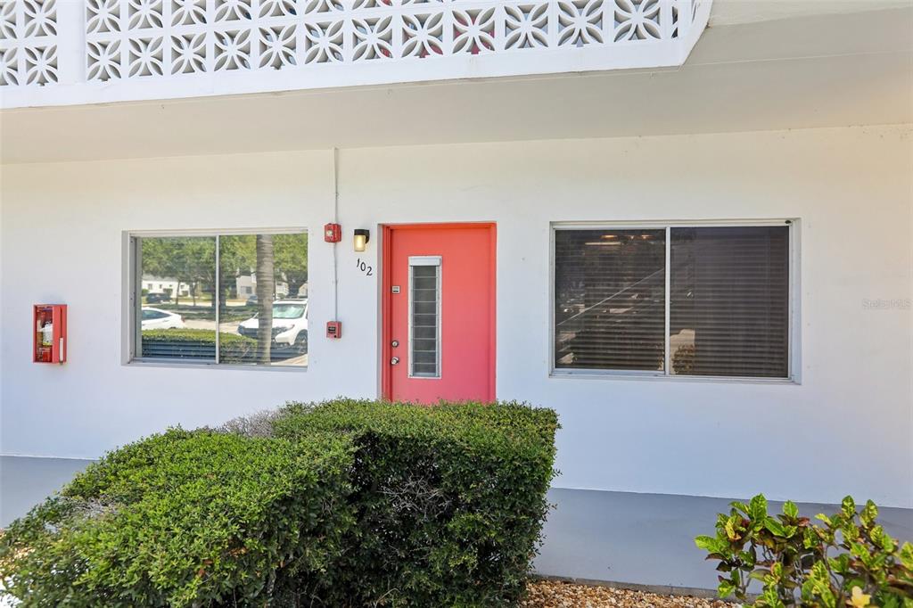 A white building exterior features a bright pink door labeled 102 and two windows — 11225 82ND AVENUE UNIT 102, SEMINOLE, FL