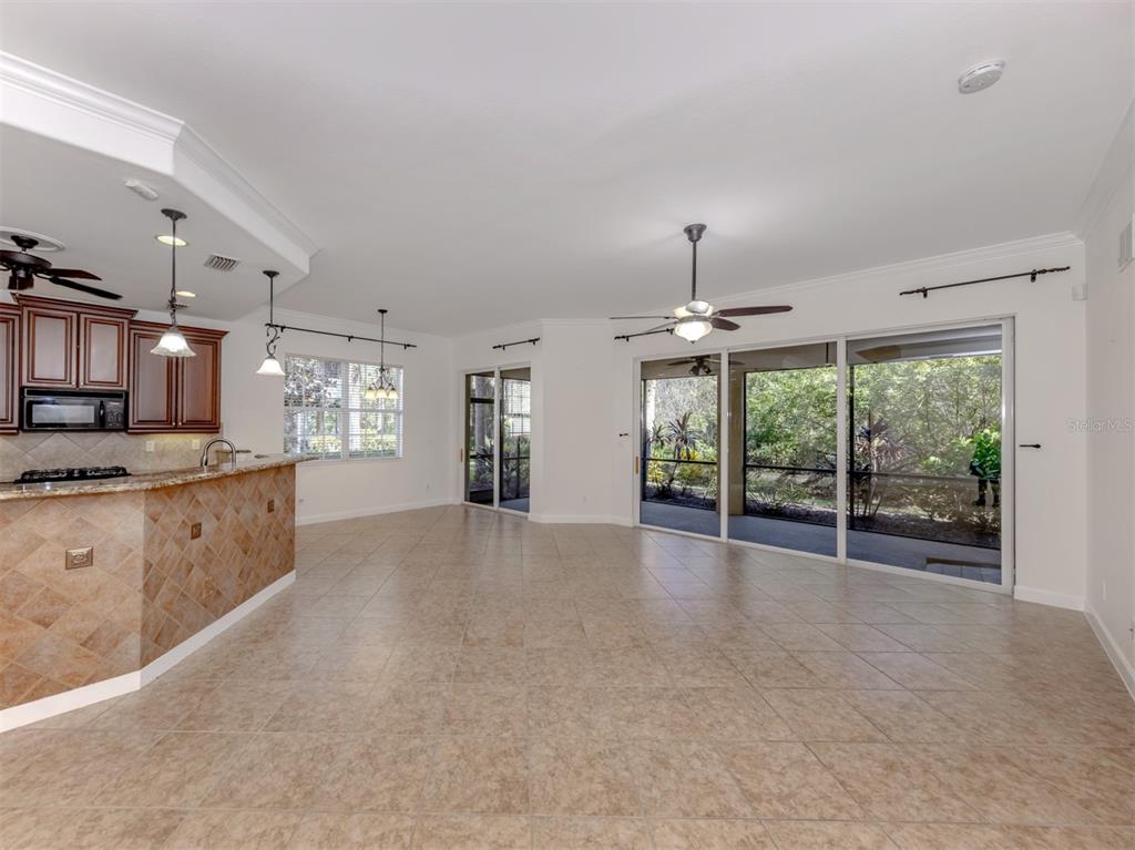 A kitchen with a tiled breakfast bar opens into a living area with sliding glass doors — 122 BELLA VISTA TERRACE UNIT 8A, NORTH VENICE, FL
