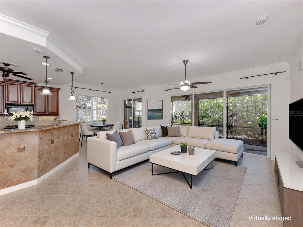 A living room with a sectional sofa, coffee table, and kitchen counter, virtually staged — 122 BELLA VISTA TERRACE UNIT 8A, NORTH VENICE, FL