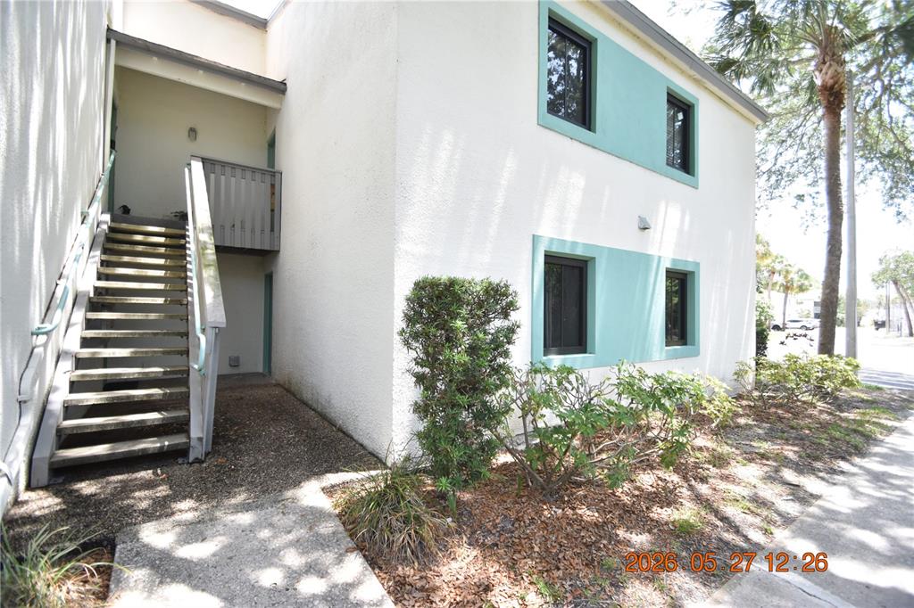 An exterior view of a two-story apartment building with a staircase leading to the second floor — 877 114TH AVENUE N UNIT 407, ST PETERSBURG, FL