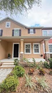 A two-story house with a tan stucco exterior, a front porch, and a dark door — 7975 NORTHLAKE PARKWAY, ORLANDO, FL