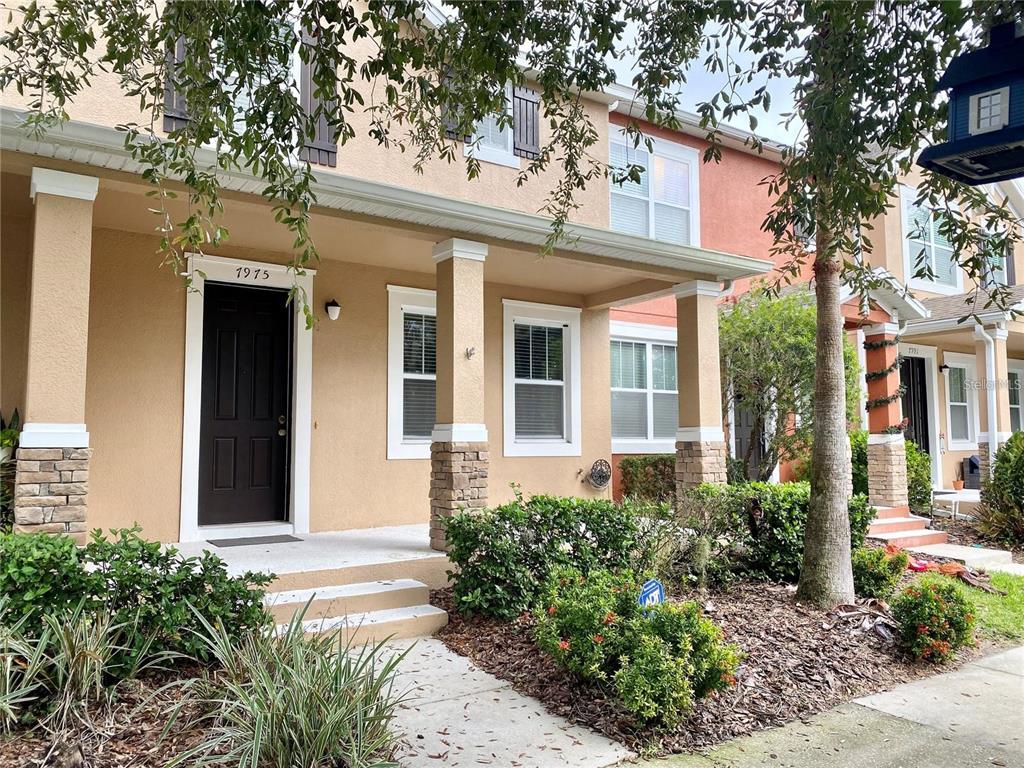A two-story townhouse exterior with a covered front porch, stone accents, and a black door — 7975 NORTHLAKE PARKWAY, ORLANDO, FL