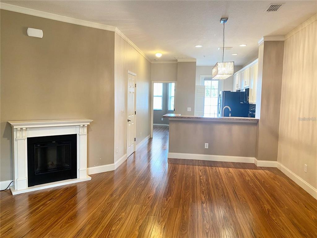 A living room with a fireplace and hardwood floors opens into a kitchen with cabinets — 7975 NORTHLAKE PARKWAY, ORLANDO, FL