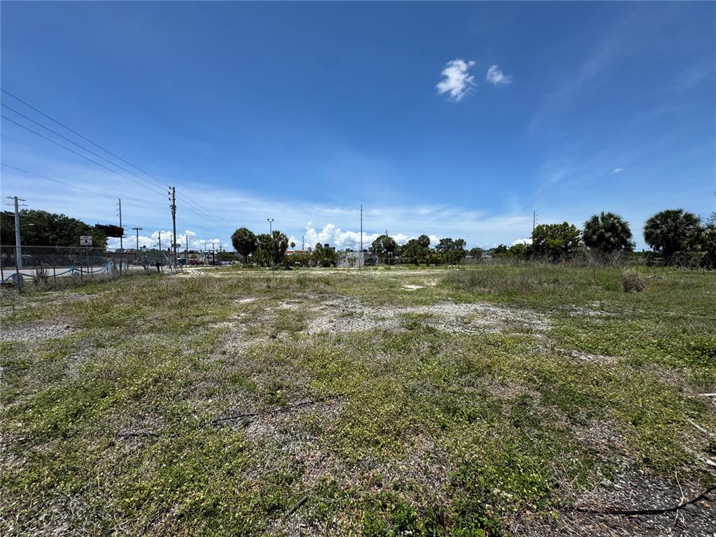A vacant, grassy lot with sparse vegetation under a bright blue sky — 8725 W WATERS AVENUE, TAMPA, FL