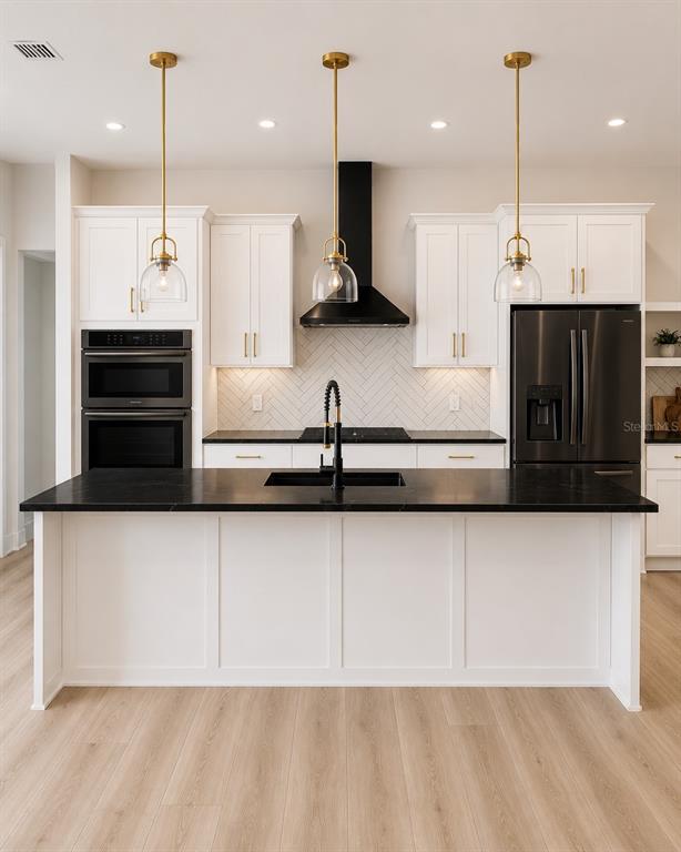 A modern kitchen features white cabinetry, a black island countertop, and three gold pendant lights — 68 ERIC DRIVE, PALM COAST, FL