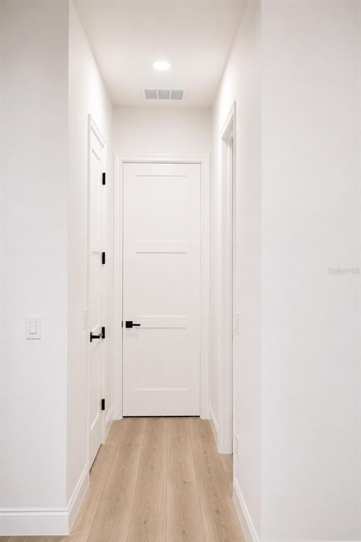 A narrow hallway features white walls, light wood flooring, and three white doors with black hardware — 68 ERIC DRIVE, PALM COAST, FL