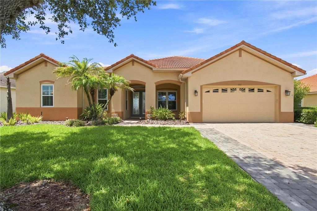 A single-story stucco house with a tile roof, two-car garage, and a paved driveway — 662 SHOREHAVEN DR, POINCIANA, FL