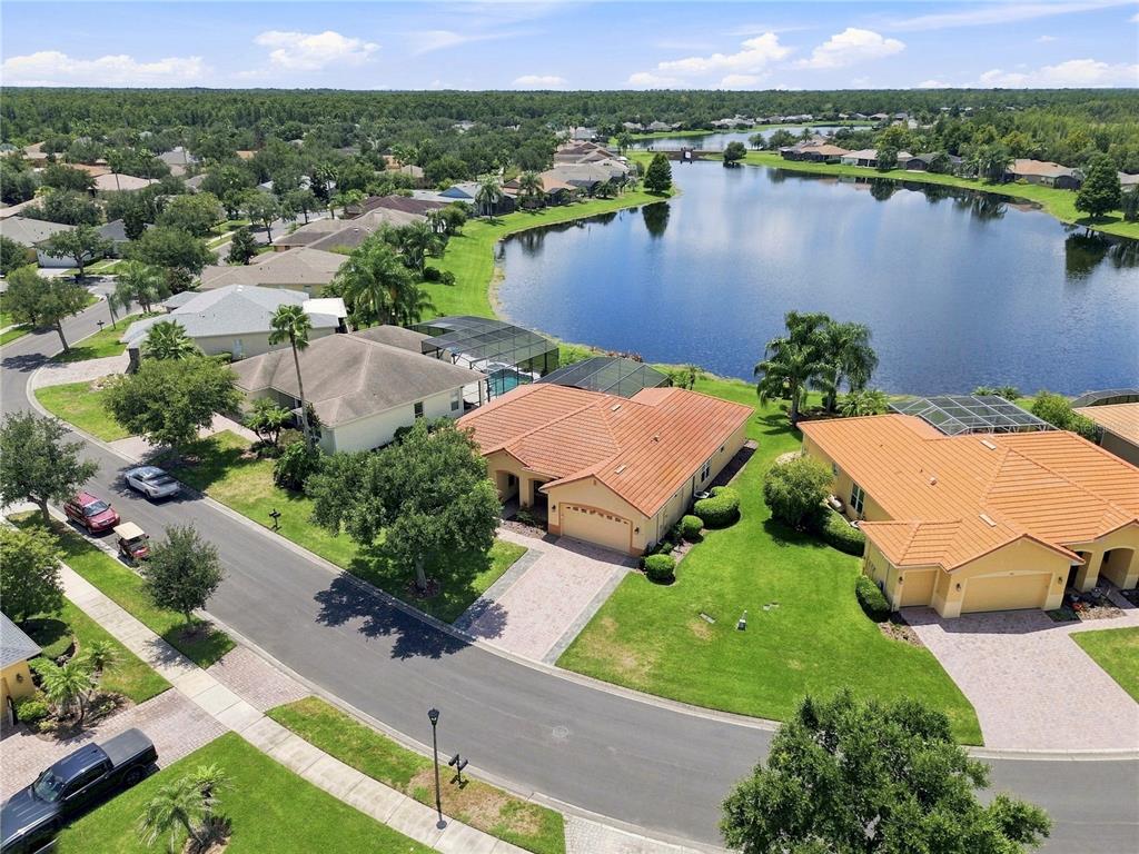 An aerial view shows suburban houses with orange tile roofs near a large lake — 662 SHOREHAVEN DR, POINCIANA, FL