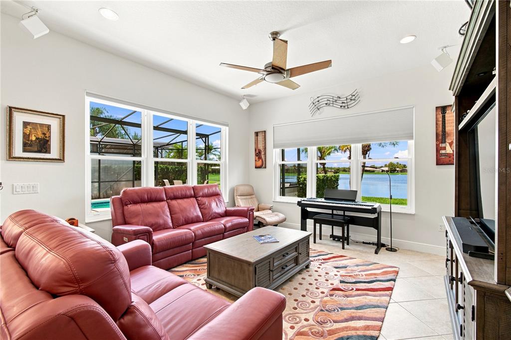 A living room features red leather sofas, a coffee table, and a piano by windows — 662 SHOREHAVEN DR, POINCIANA, FL