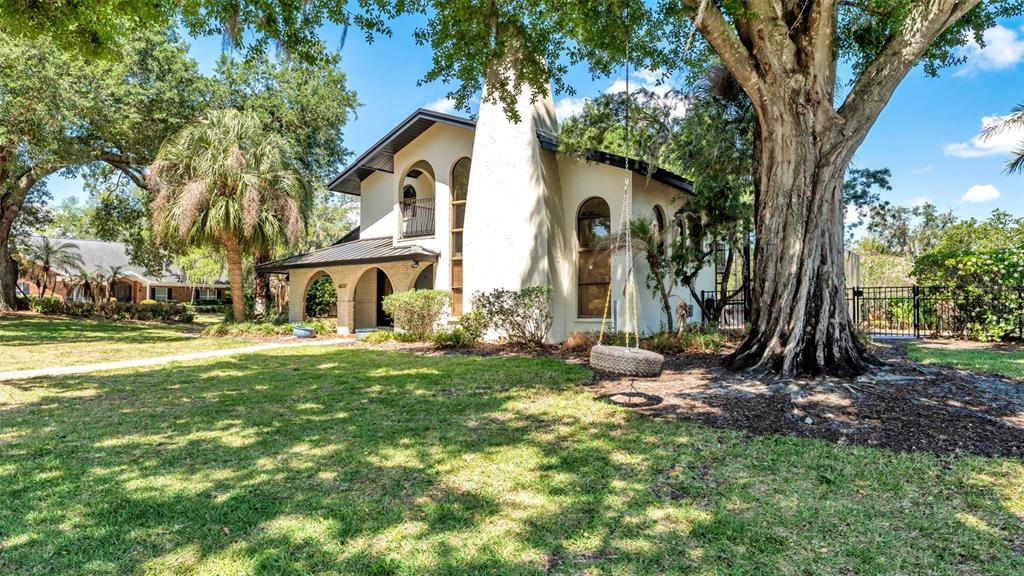 A two-story stucco house with a large chimney and a tire swing hanging from a tree — 6037 CRICKET DRIVE, LAKELAND, FL