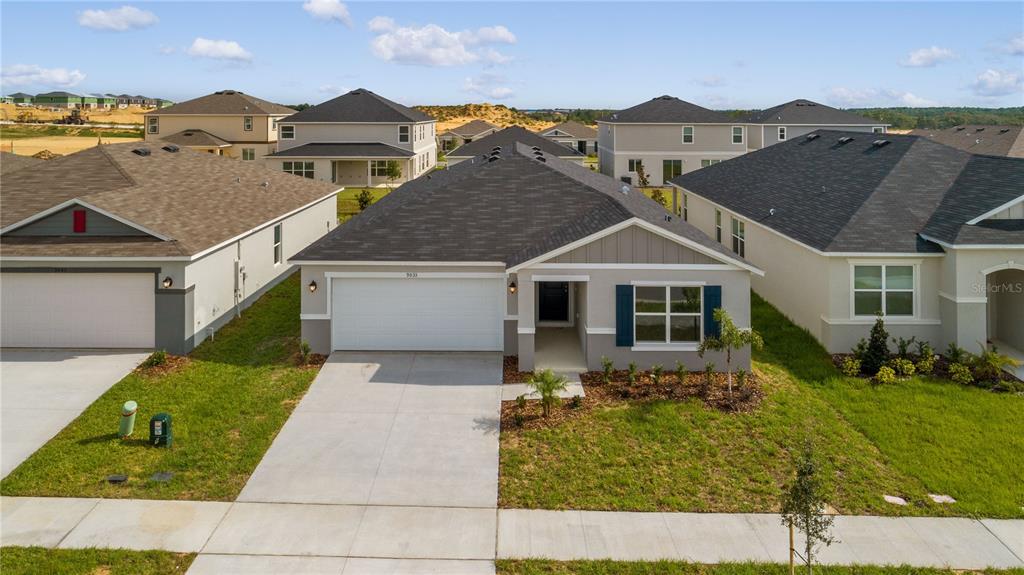A single-story suburban house with a two-car garage, gray siding, and a dark shingled roof — 9033 HOOTON WAY, DAVENPORT, FL