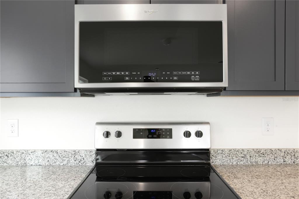 A stainless steel Whirlpool microwave sits above a matching electric range in a kitchen — 9033 HOOTON WAY, DAVENPORT, FL