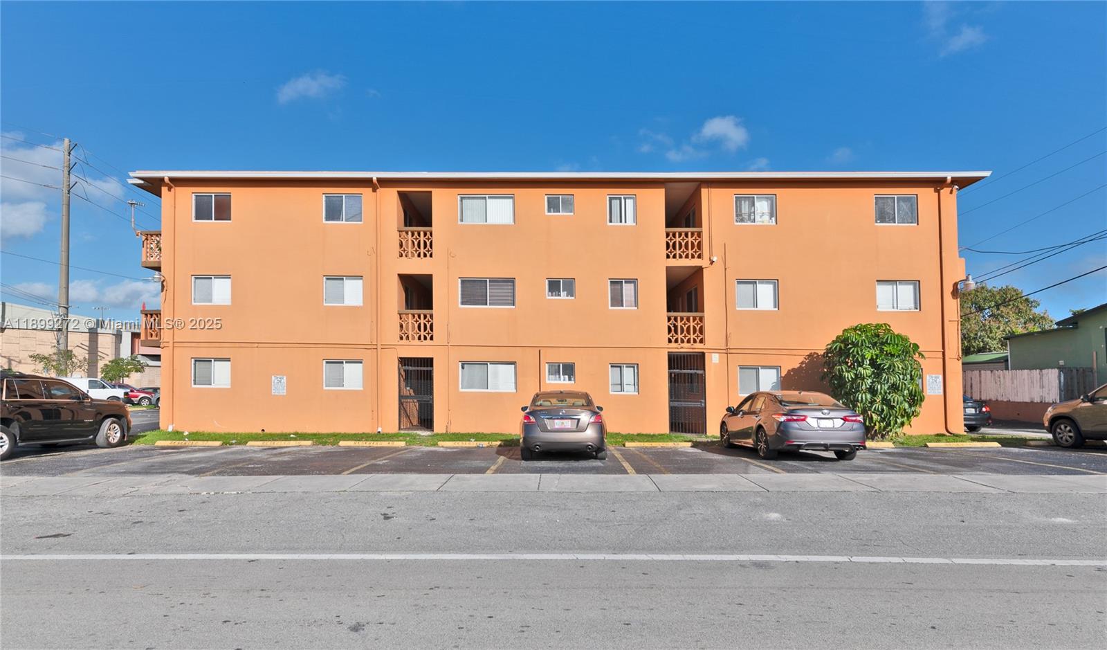 A three-story orange apartment building features a parking lot in the foreground — 2330 NW 11th St # 46, Miami FL 33125, MIAMI, FL