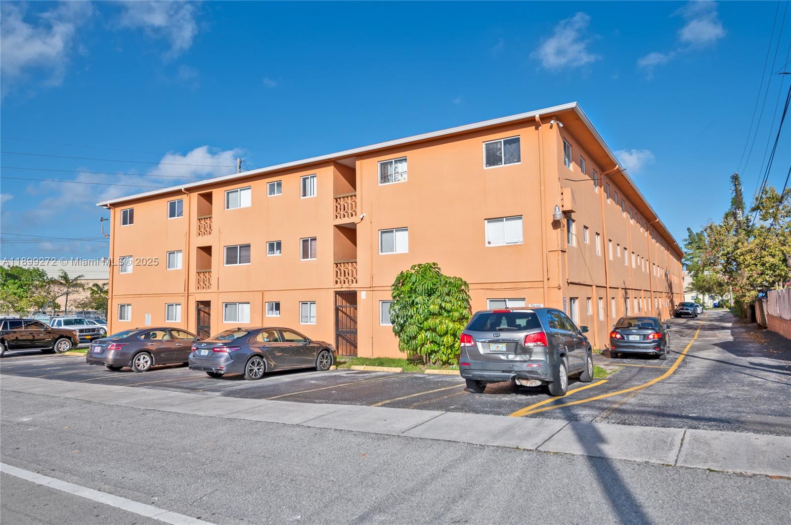 A three-story orange apartment building features a parking lot with several parked cars — 2330 NW 11th St # 46, Miami FL 33125, MIAMI, FL