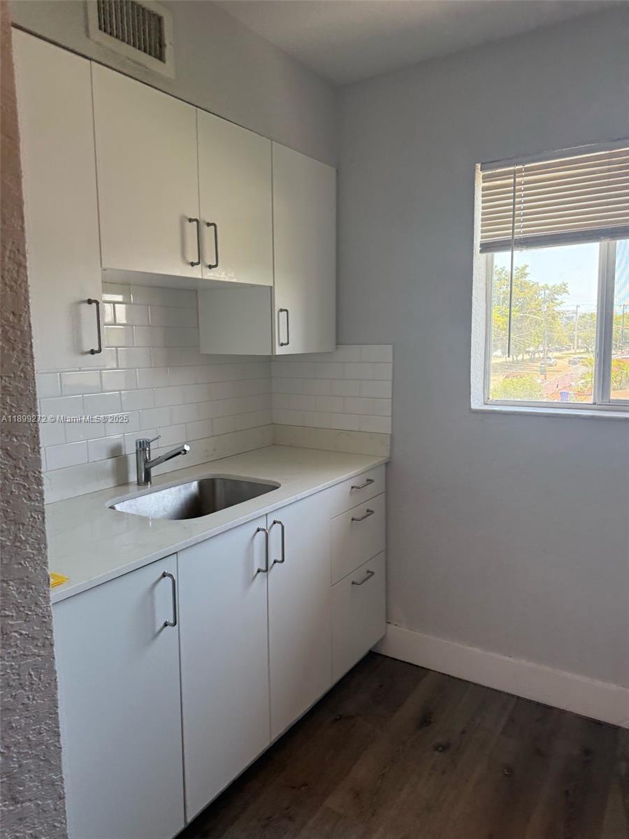 A small kitchen features white cabinets, a stainless steel sink, and white subway tile backsplash — 2330 NW 11th St # 46, Miami FL 33125, MIAMI, FL