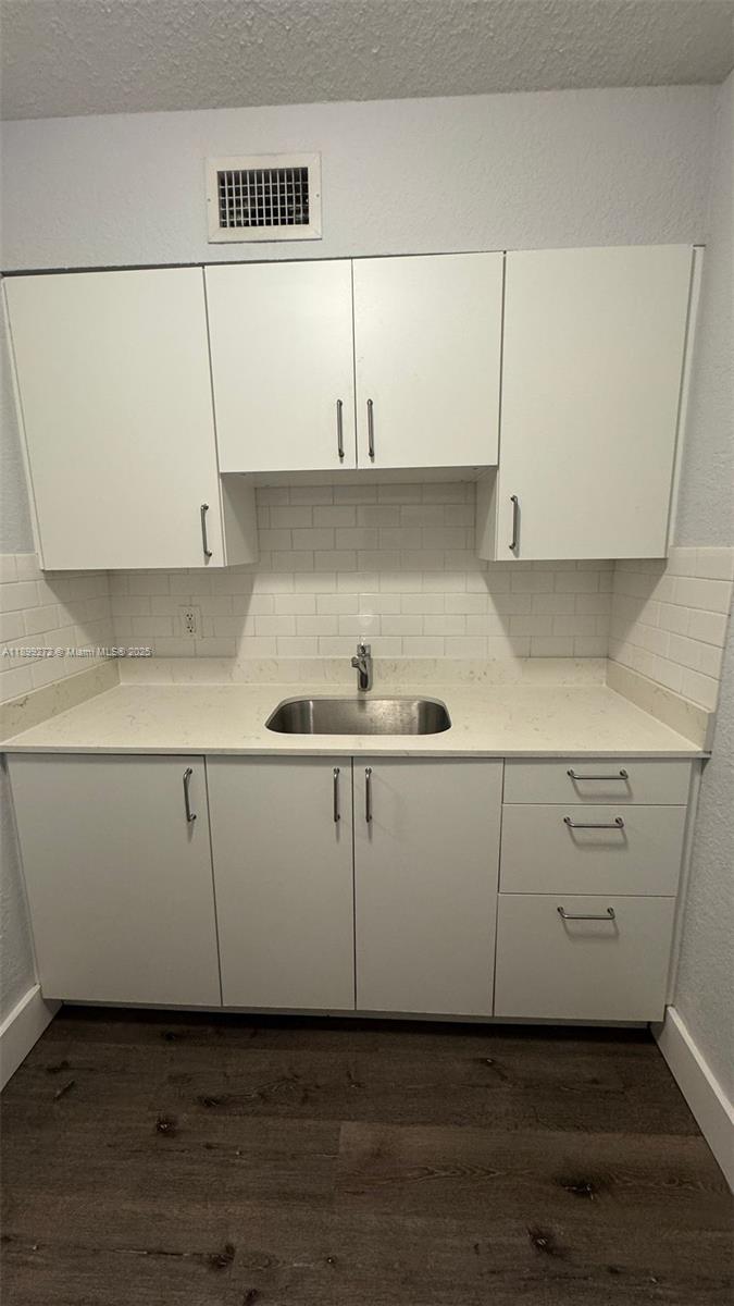 A small kitchen features white cabinets, a stainless steel sink, and a white backsplash — 2330 NW 11th St # 46, Miami FL 33125, MIAMI, FL