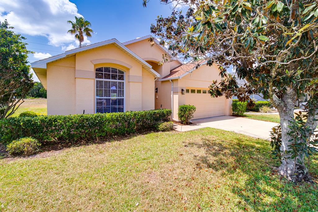 A single-story house with a tan stucco exterior, a two-car garage, and a front lawn — 19756 GLEN ELM WAY, ORLANDO, FL