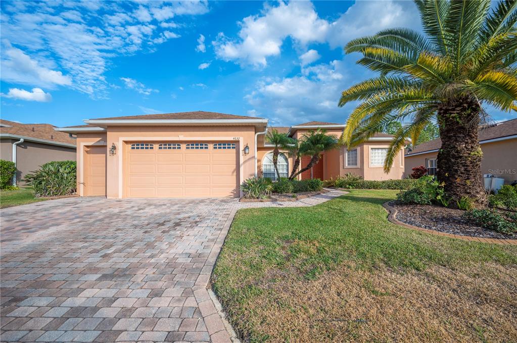 A single-story house with a paved driveway, a two-car garage, and a large palm tree — 4632 TURNBERRY LANE, LAKE WALES, FL
