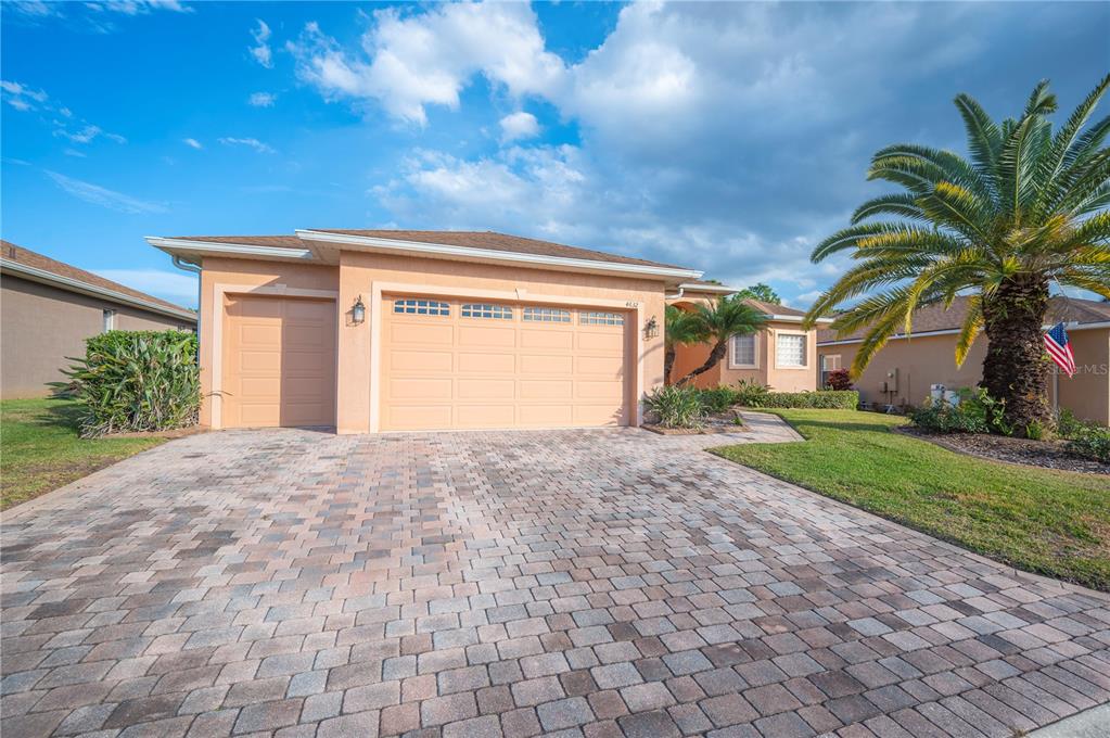 A single-story house with a paved driveway, a two-car garage, and a large palm tree — 4632 TURNBERRY LANE, LAKE WALES, FL