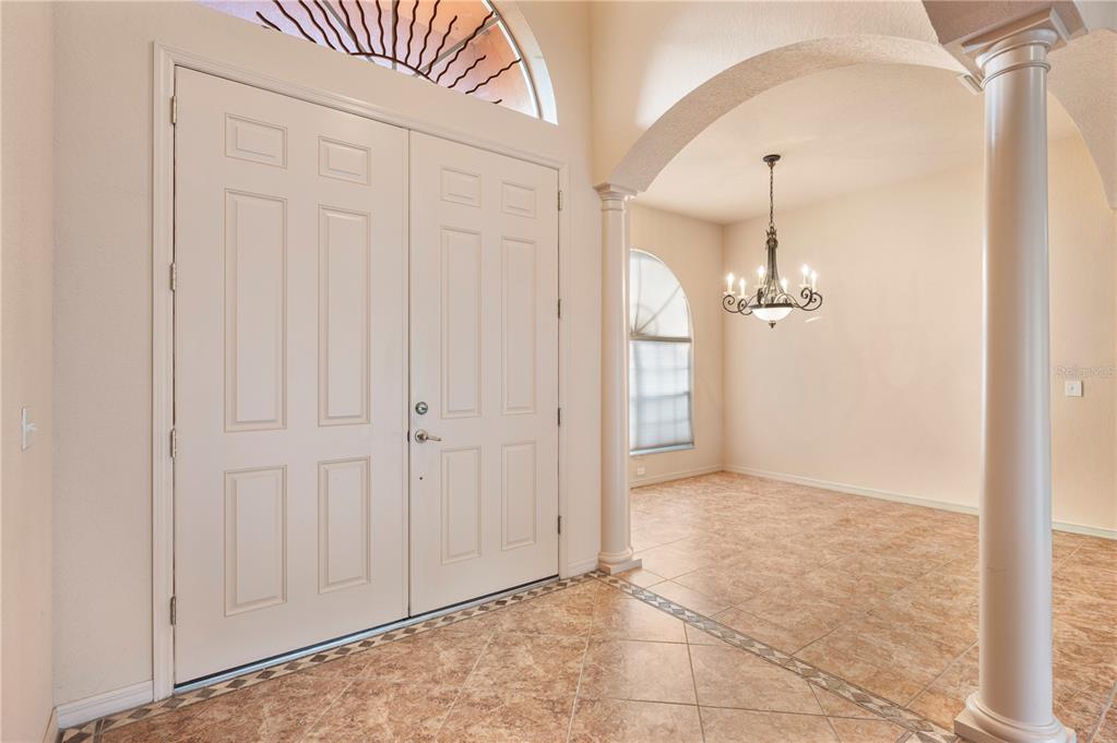 An entryway with tiled floors, double doors, and a dining area with a chandelier — 4632 TURNBERRY LANE, LAKE WALES, FL