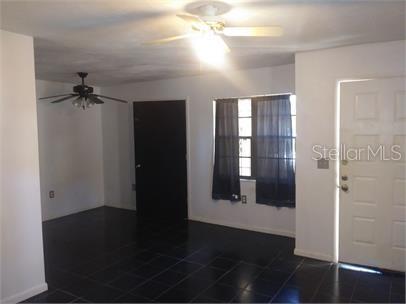 A room with black tile flooring, a ceiling fan, a window with curtains, and a door — 1723 SW 68TH TERRACE, GAINESVILLE, FL