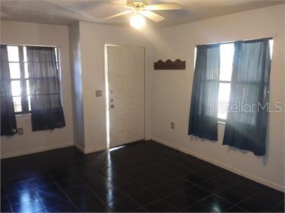 A room with dark tile flooring, a ceiling fan, a white door, and two windows — 1723 SW 68TH TERRACE, GAINESVILLE, FL