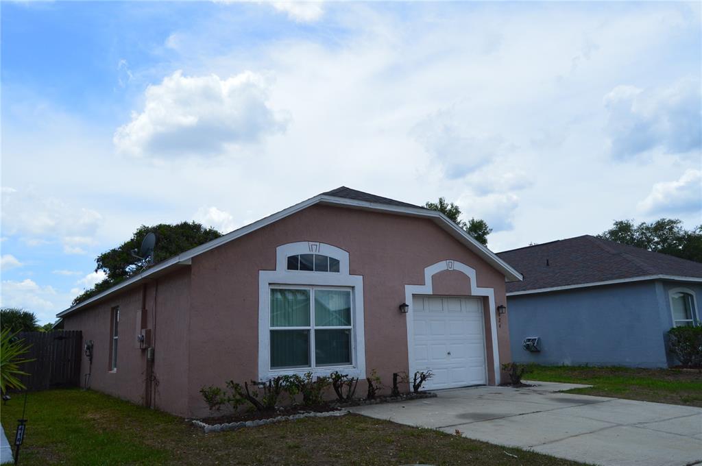 A single-story, pink stucco house features a white garage door and a front window — 424 DELICATA DRIVE, ORLANDO, FL