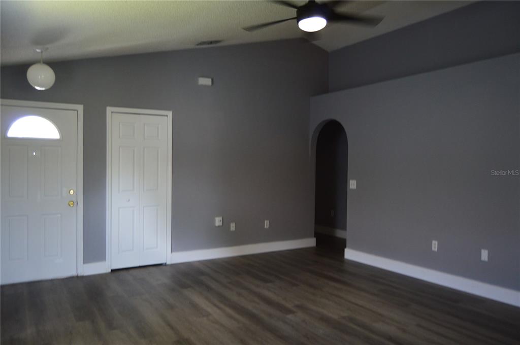 A living room with gray walls, wood-look flooring, a vaulted ceiling, and an arched doorway — 424 DELICATA DRIVE, ORLANDO, FL