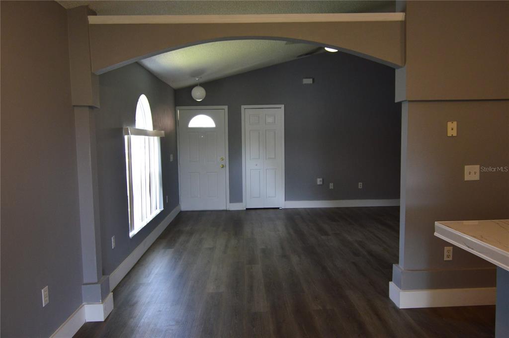 An interior view of a living area with gray walls, wood-look flooring, and an arched entryway — 424 DELICATA DRIVE, ORLANDO, FL