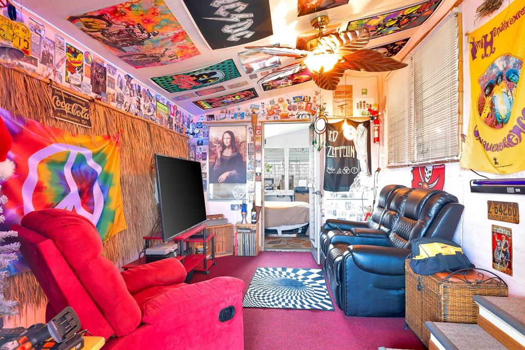 A room with a red recliner, black leather sofa, television, and walls covered in posters — 515 50TH AVENUE TERRACE W, BRADENTON, FL